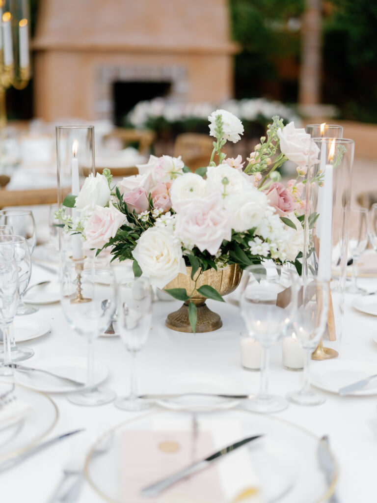 Wedding reception centerpiece in gold vase of white and blush flowers.