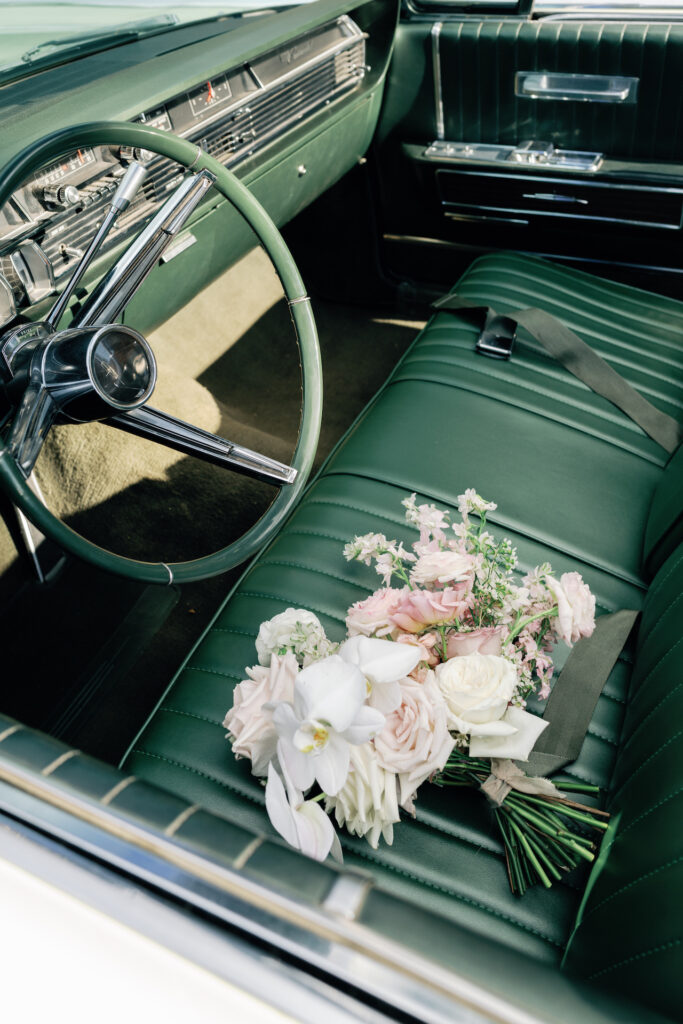 Bridal bouquet sitting in driver's seat of vintage car.