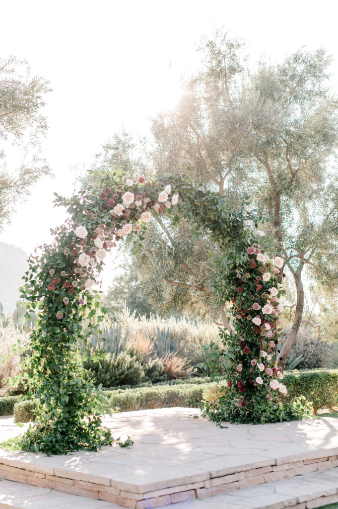 Wedding ceremony arch at altar with greenery and floral installed on it.