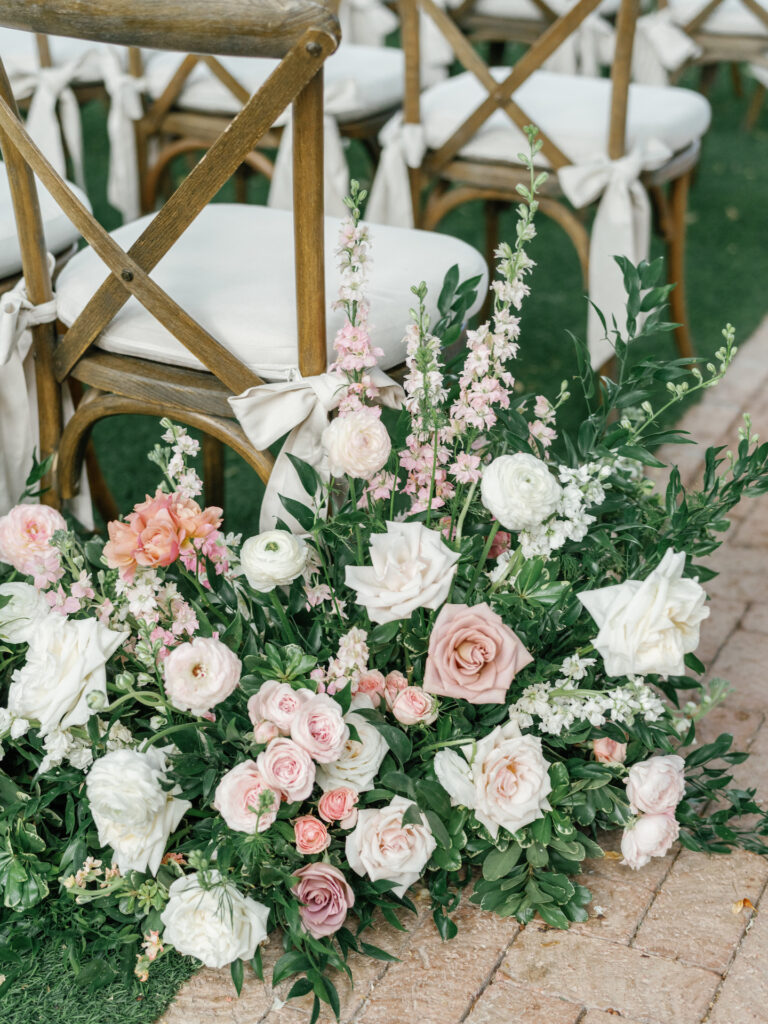 Ground aisle floral arrangements of pink and white flowers.