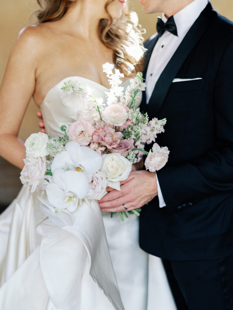 Bride and groom with bride holding bouquet of white and pink flowers.