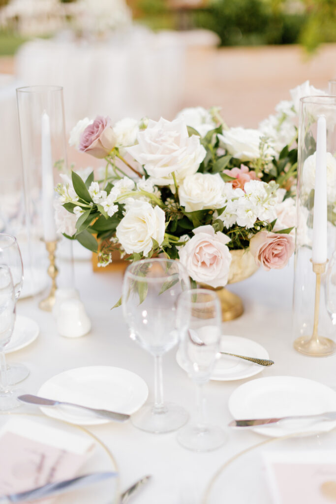Wedding reception centerpiece in gold vase of white and soft pink flowers.