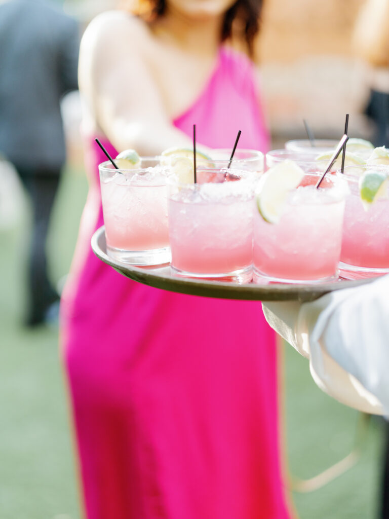 Wedding cocktails tray filled with glasses of pink drinks.