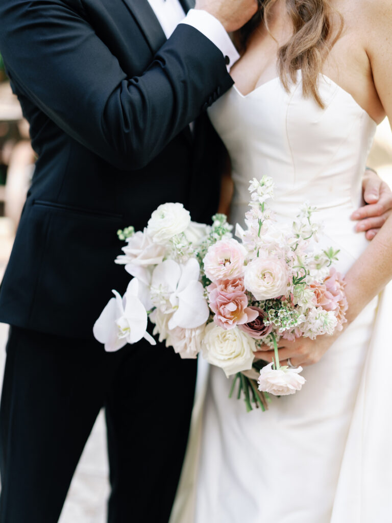 Bride and groom with bride holding bouquet of white and blush pink flowers.