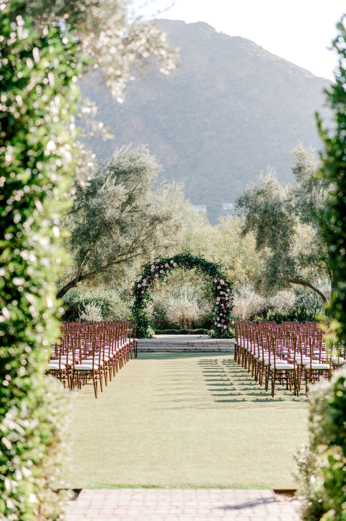 Wedding ceremony arch at altar with greenery and floral installed on it.
