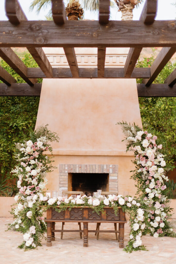 Royal Palms fire place and sweetheart table with framing floral columns and table garland.