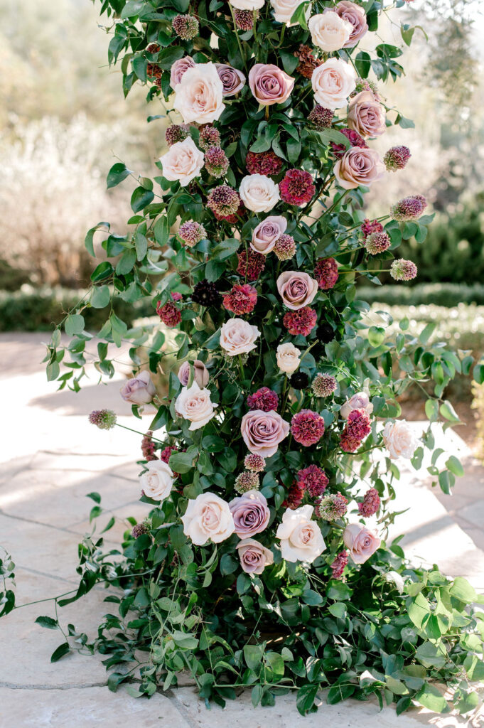Close up image of wedding ceremony arch with pink and mauve flowers.