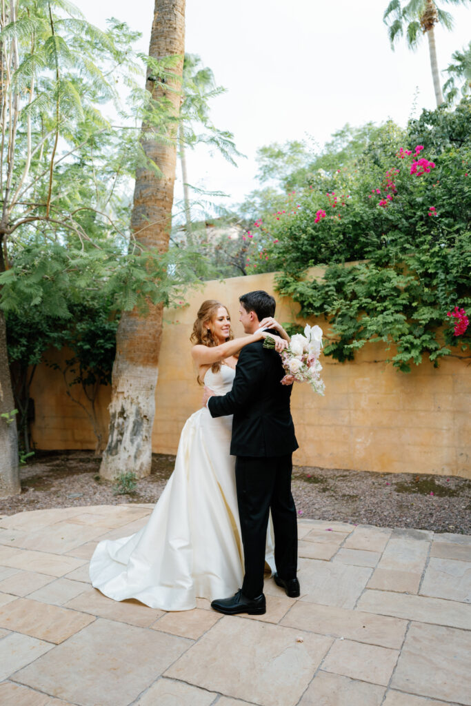 Bride and groom embracing on tiled outdoor space at Royal Palms.