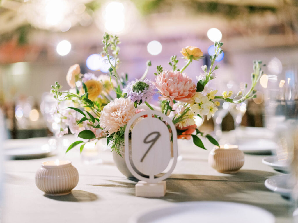 Reception table centerpiece of flowers with table number in front of it.