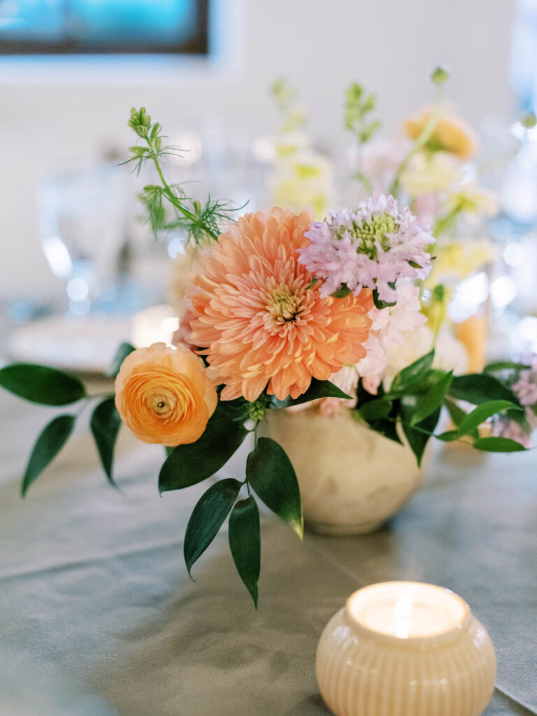Reception centerpiece flowers of peach and purple with greenery.