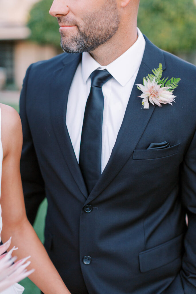Groom wearing tropical style boutonniere in dark blue suit.