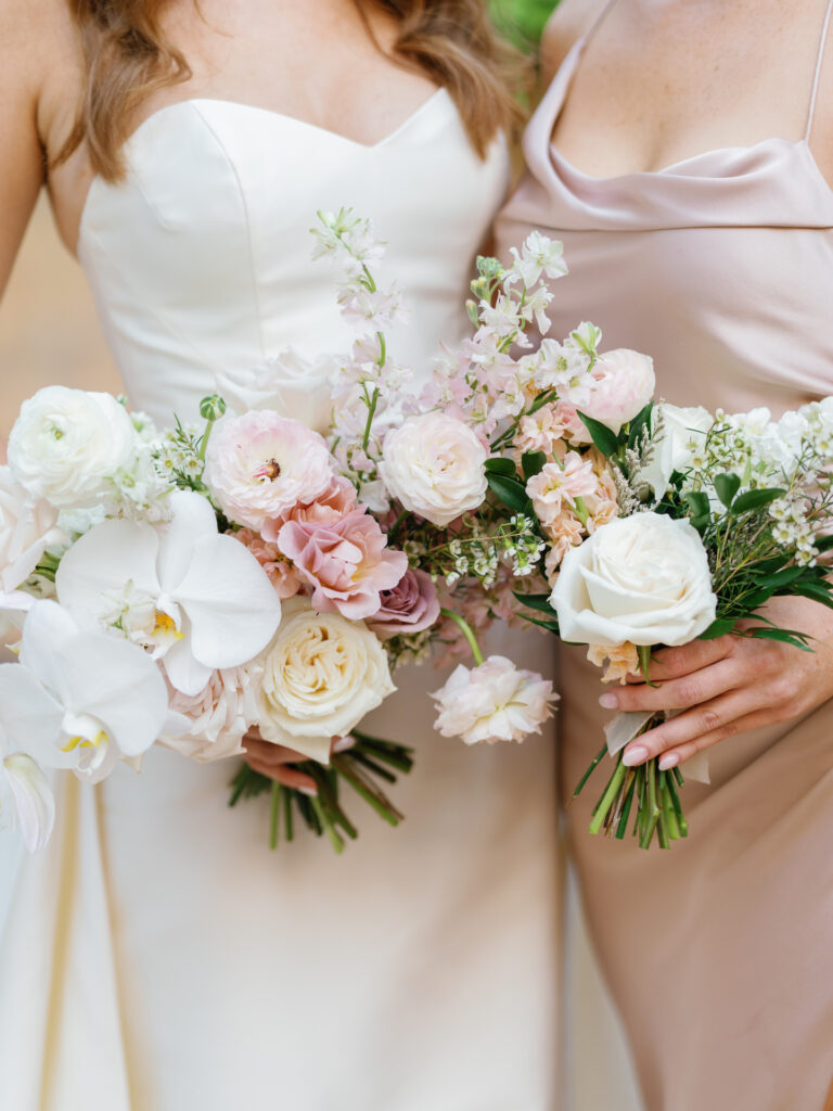 Bride standing with bridesmaid in pink dress, both holding bouquets.