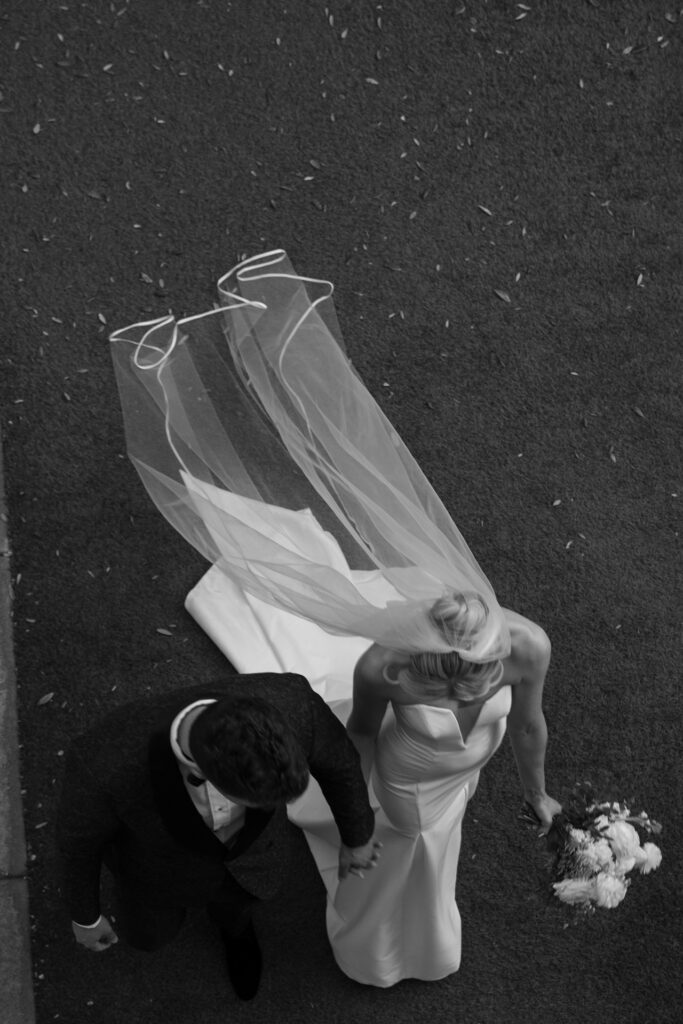 Overhead image of bride and groom walking holding hands.