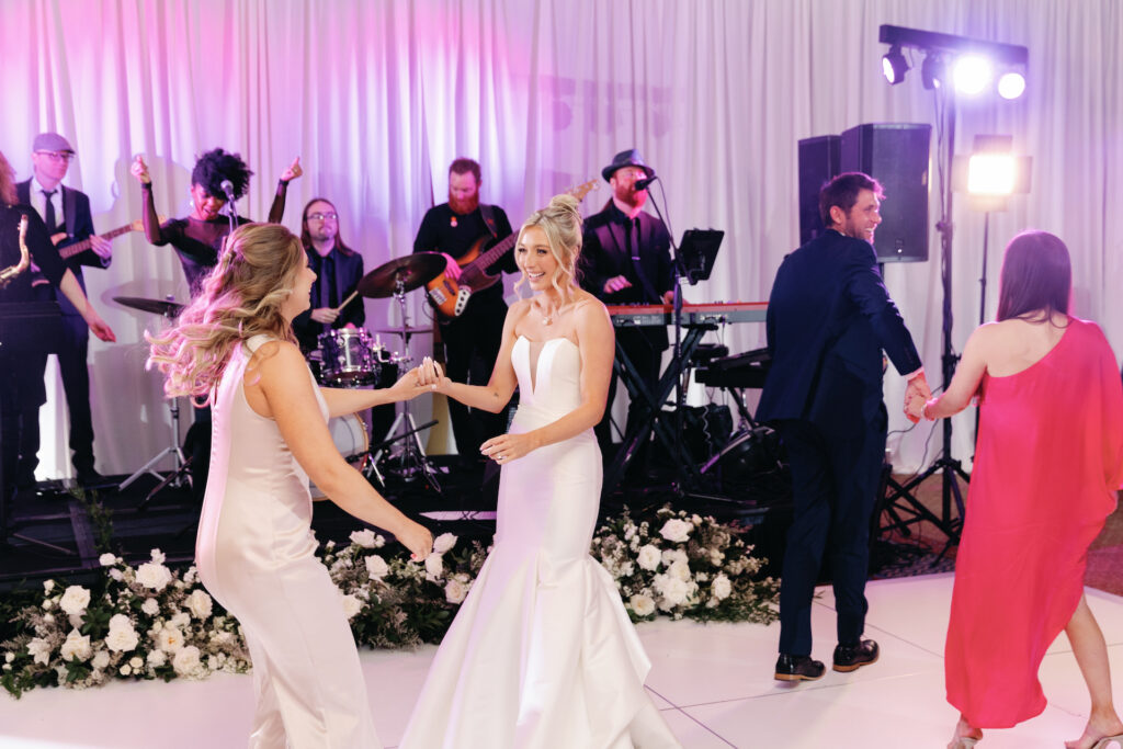 Bride dancing in front of live band with other guests around her.