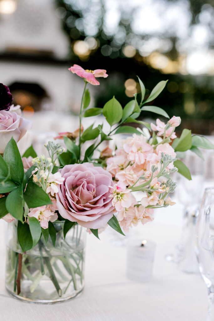 Wedding reception centerpiece in glass vase of mauve, pink, blush and burgundy flowers.