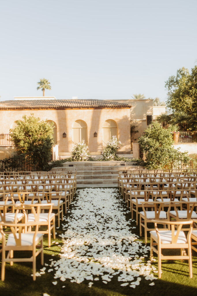 Royal Palms outdoor ceremony space with altar space up steps in front and thick white rose petals covering aisle.