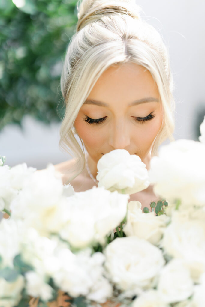 Bride smelling white roses bouquet with eyes closed.