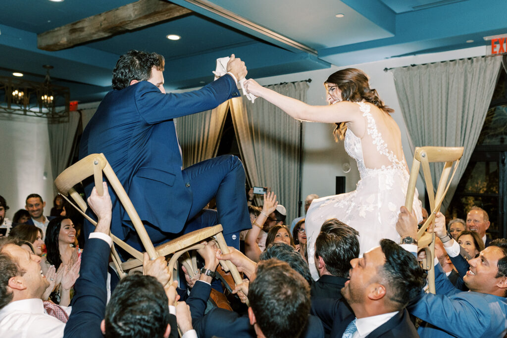Wedding reception bride and groom lifted up on chairs.