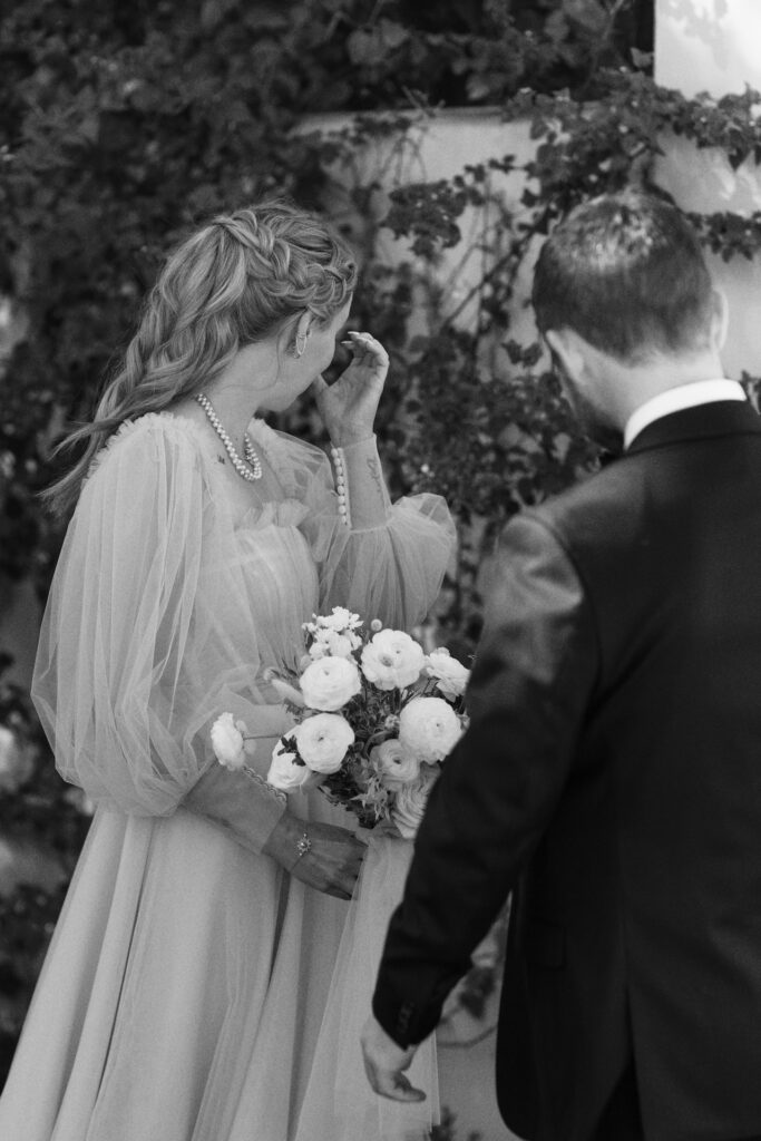Bride looking away from groom, wiping tears away.