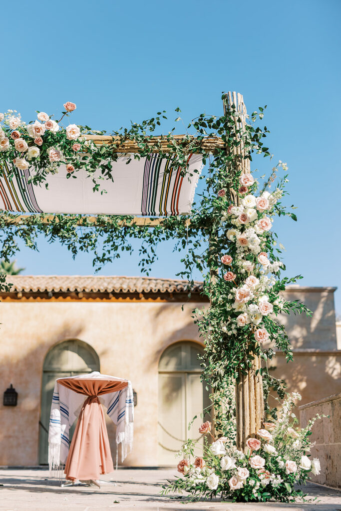 Custom dried saguaro chuppah with floral installation and cloth covering on top.