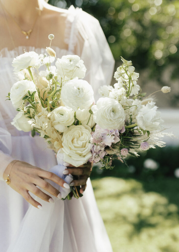 Lush bridal bouquet of varied white flowers and light purple.