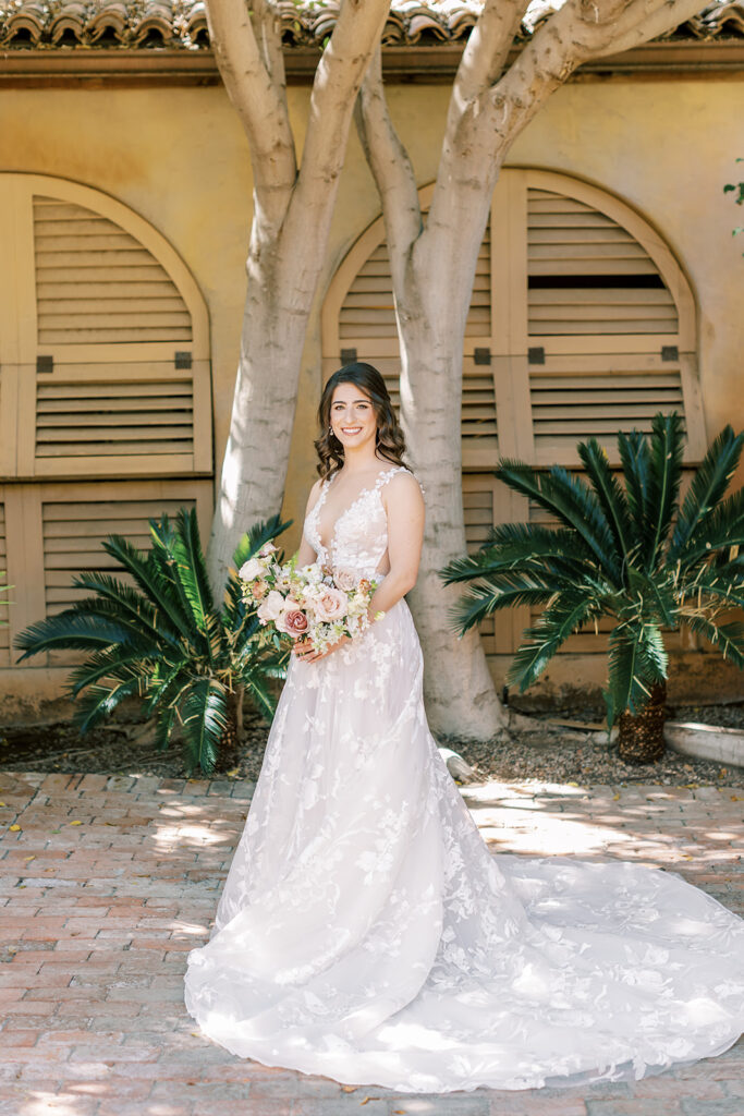Bride standing at Royal Palms in front of landscape looking off to side while holding bouquet.