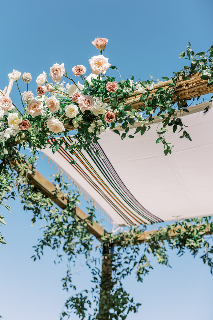 Floral installed on wedding chuppah of white and blush.