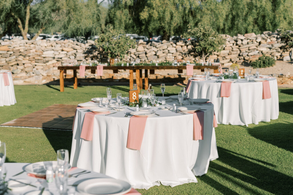 Outdoor reception space at McDowell Mountain with round reception tables with white linen and pink napkins.