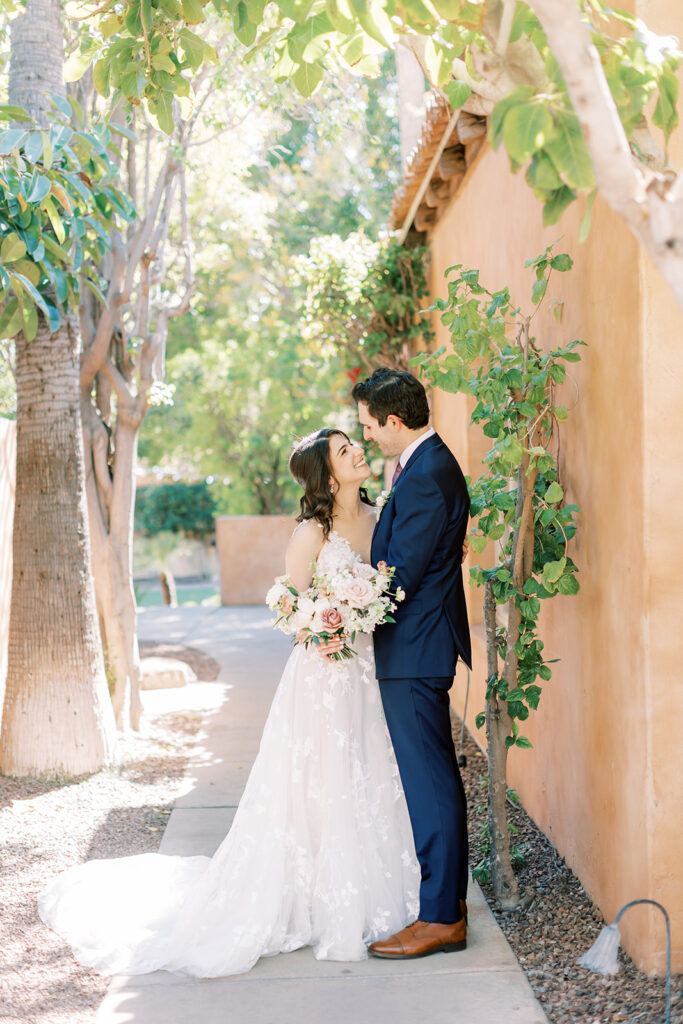 Bride and and groom embracing on path at Royal Palms, bride holding bouquet.