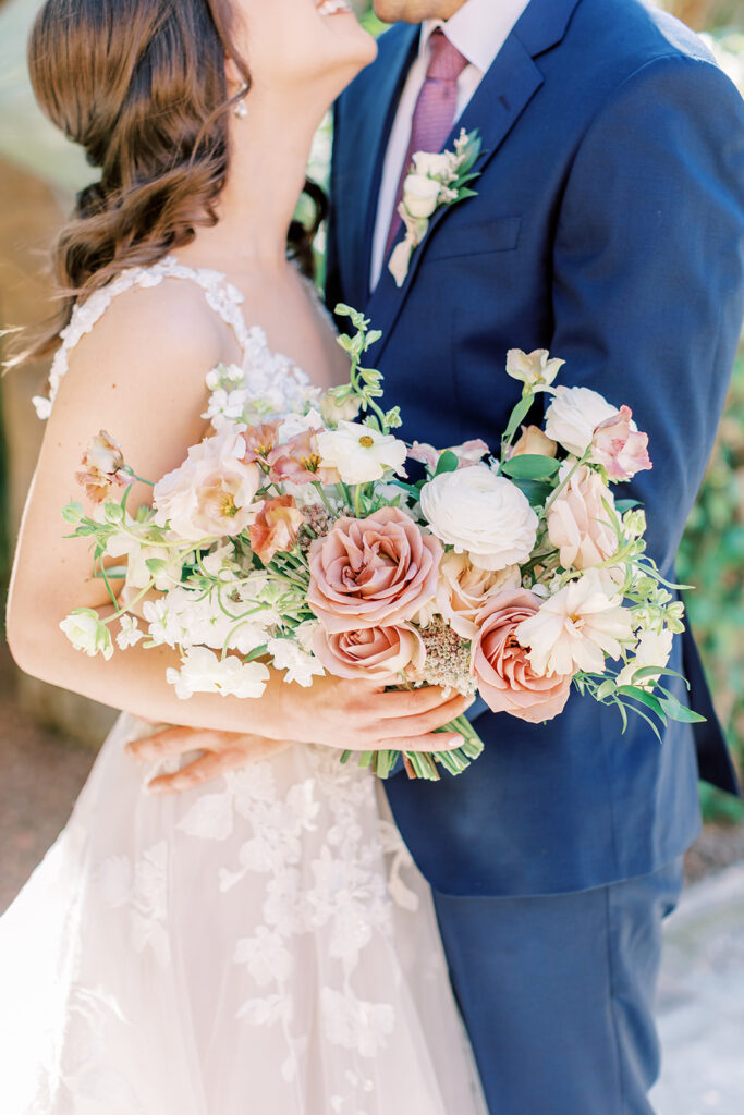 Lush bridal bouquet held by bride of white and blush pink flowers, including roses.