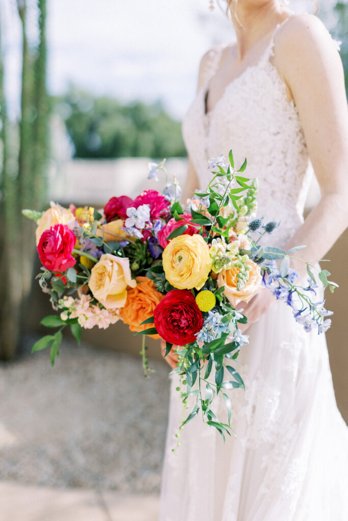 Bridal bouquet of vibrant colors including fuchsia, yellow, peach, purple, and blue.