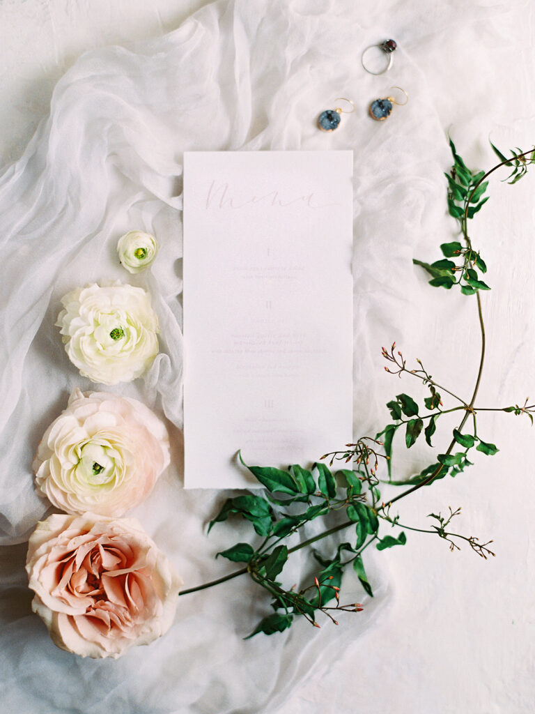 Wedding menu on white stationary with flowers around it.