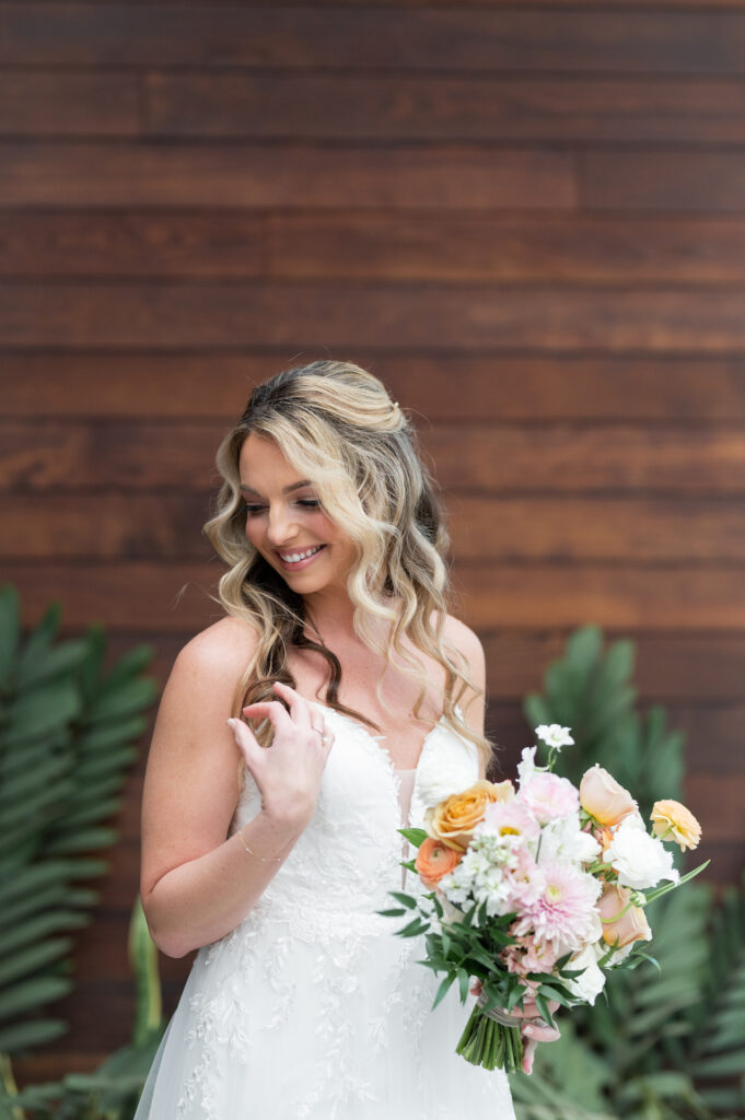 Bride looking down and to side, smiling and holding bridal bouquet.