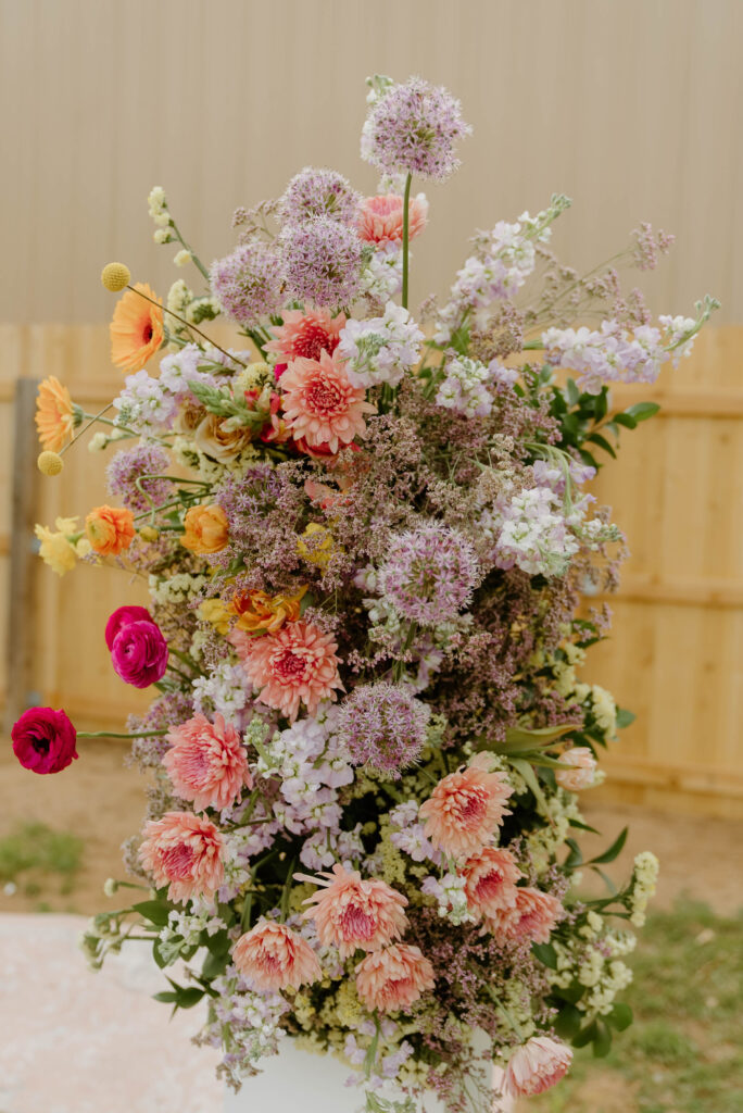 Floral column installation at wedding ceremony of allium, ranunculus, mums and greenery.