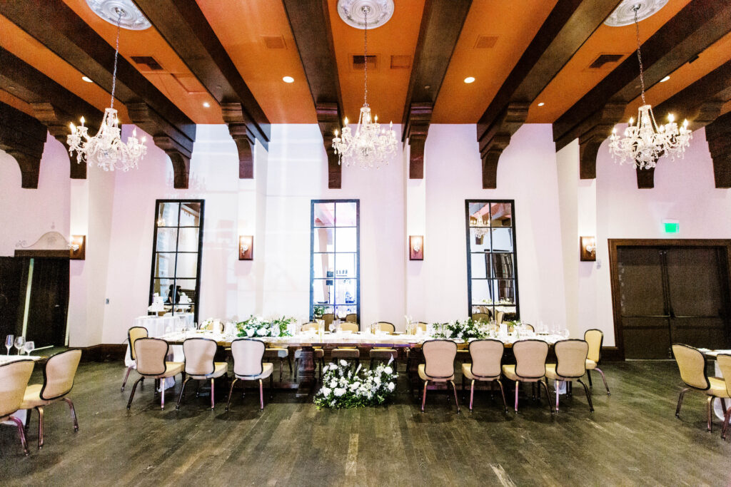 Long indoor reception tables with centerpieces of white flowers and greenery at Omni Montelucia resort.