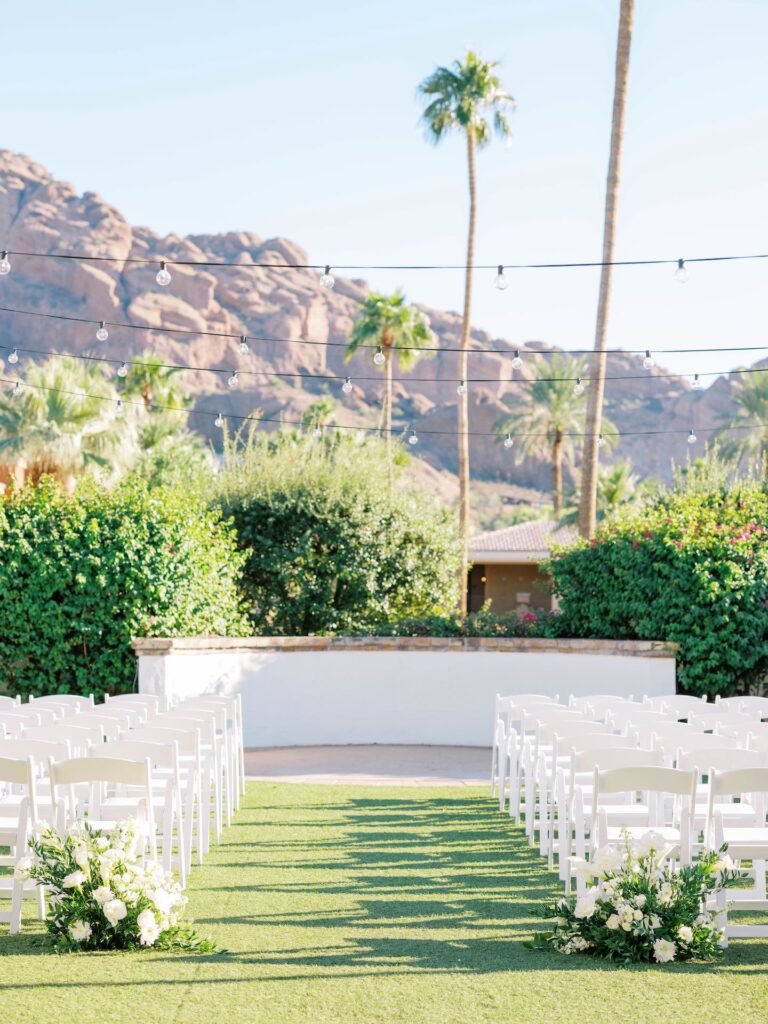 Outdoor wedding ceremony space with back of aisle ground floral arrangements at Omni Montelucia.