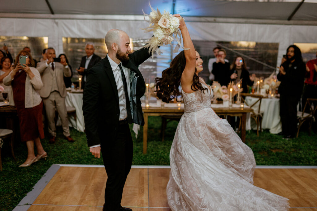 Bride and groom dancing on dance floor in tent wedding reception space.