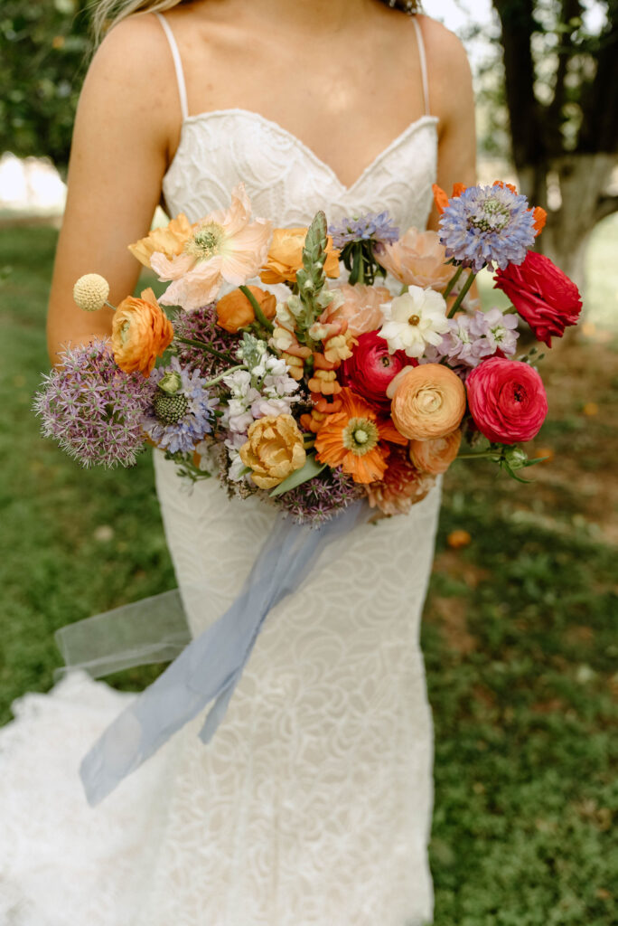 Bridal bouquet of lush pink, white, lavender and orange hued floral.