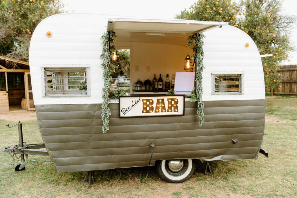 Mobile bar in camper at outdoor wedding.