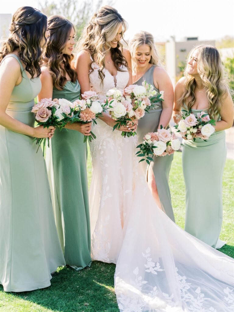 Bride standing in a row with bridesmaids in various shades of mint green, all holding bouquets.