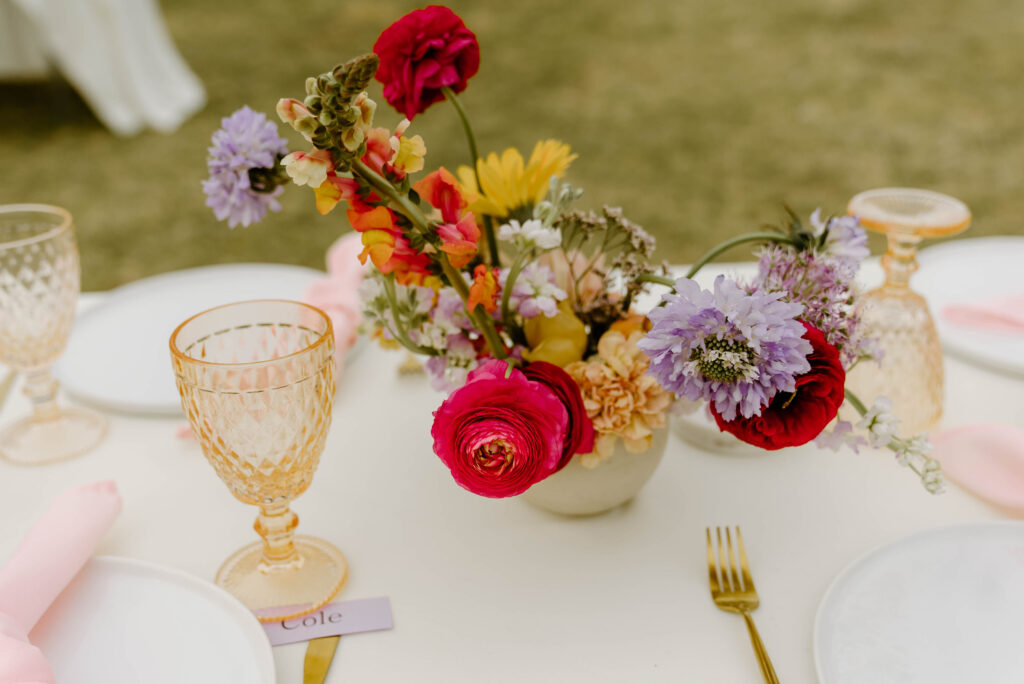 Colorful wedding reception centerpiece of yellow, pink, and lavender flowers.