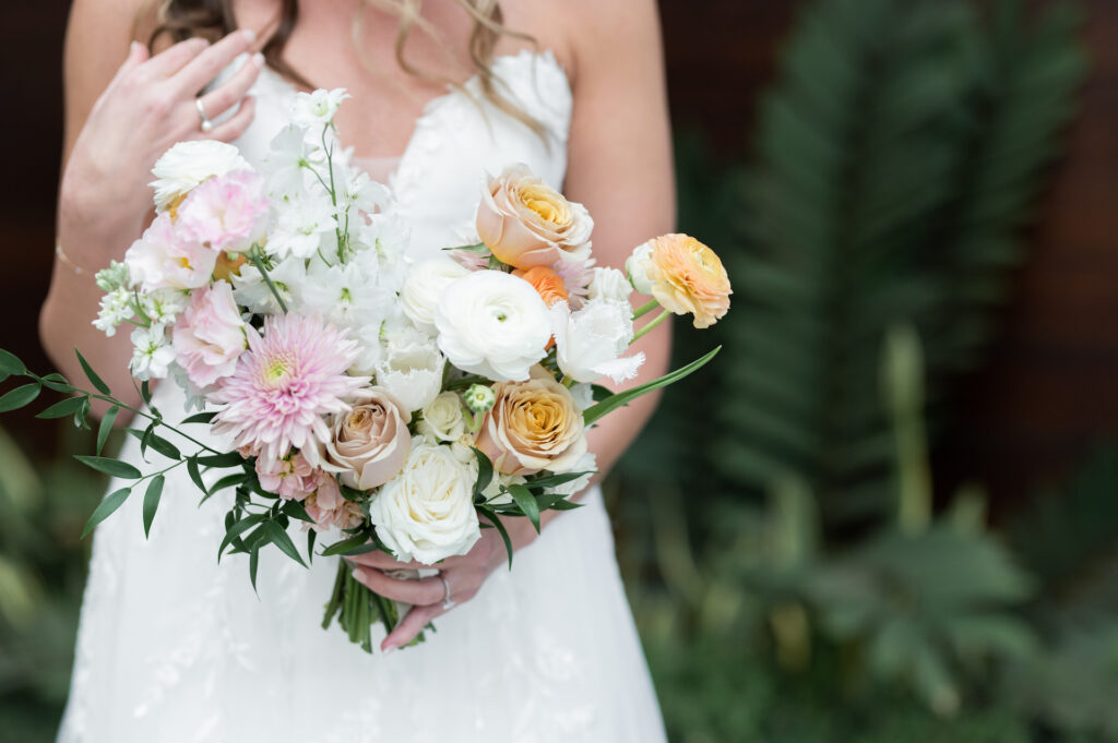 Bridal bouquet of white, pink, and yellow colors including roses, mums, tulips and ranunculus flowers.