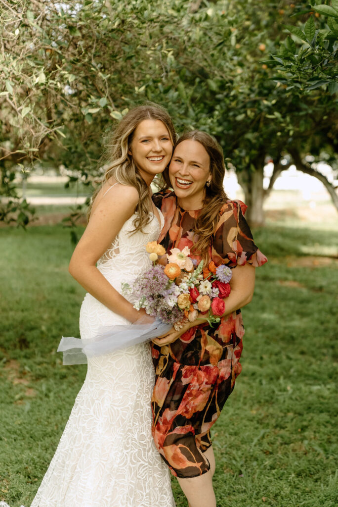 Allison of Array Design with bride in gown standing grass field with trees behind them.