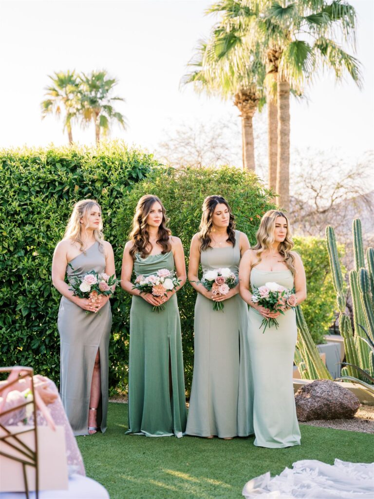 Bridesmaids standing in a line during outdoor wedding ceremony at Sanctuary resort, wearing shades of mint green.