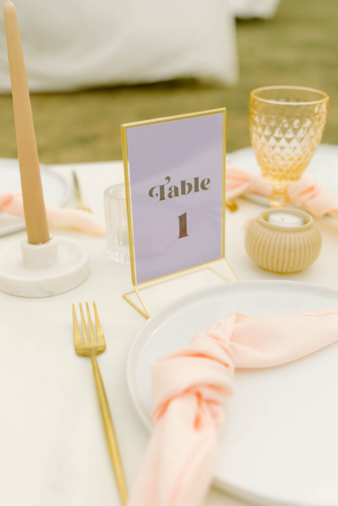 Purple table number in gold holder on wedding reception table.