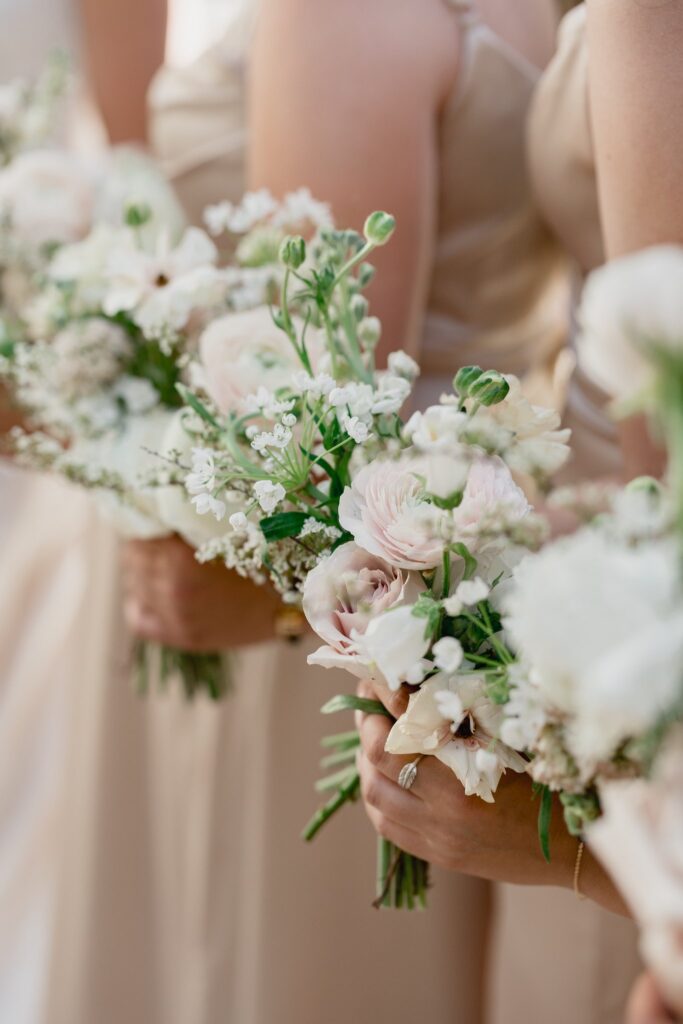 Bridesmaid bouquets of white and blush floral with greenery .