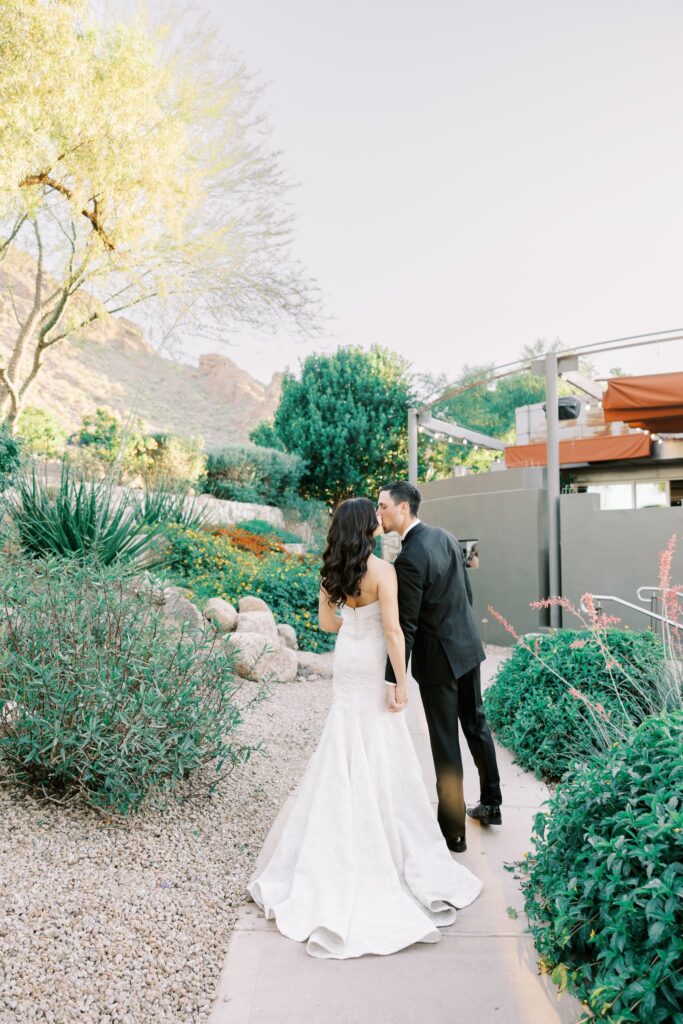 Bride and groom kissing on cement path in desert landscape at Sanctuary Resort.