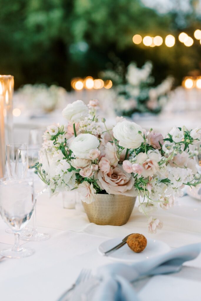 Wedding reception centerpiece in gold vase of white and blush floral.