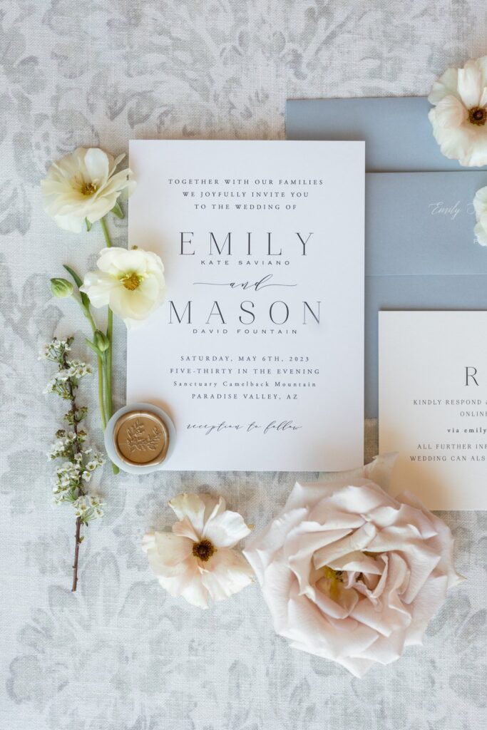 Neutral wedding invitation suite in white, cream, and gray, with floral accents.