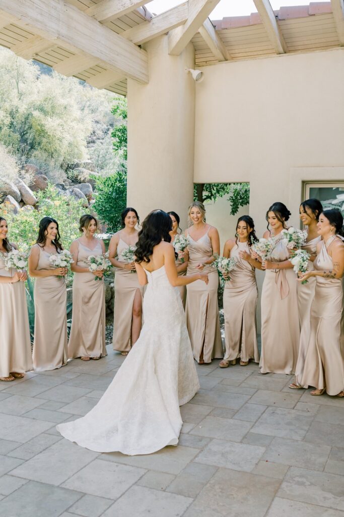 Bride standing in front of bridesmaids in a u-shaped line, all holding bouquets.